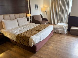 Chambre d’hôtel avec lit double, fauteuil et parquet, équipée selon les normes de classement